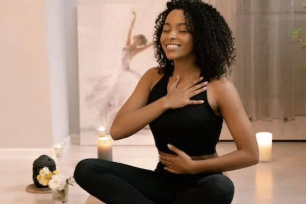 Donna sorridente con mano sul cuore e sulla pancia: lo yoga ci aiuta a vincere lo stress e a cominciare a vivere bene